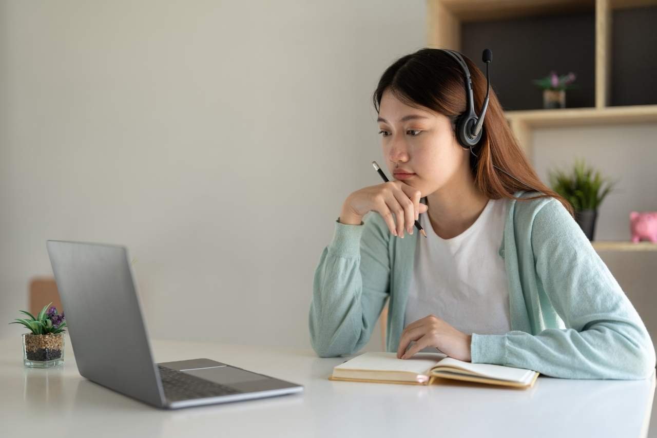 Young woman using a laptop with a headset for online work or learning, reflecting Mudita Technicals’ commitment to shaping your digital future with expertise.